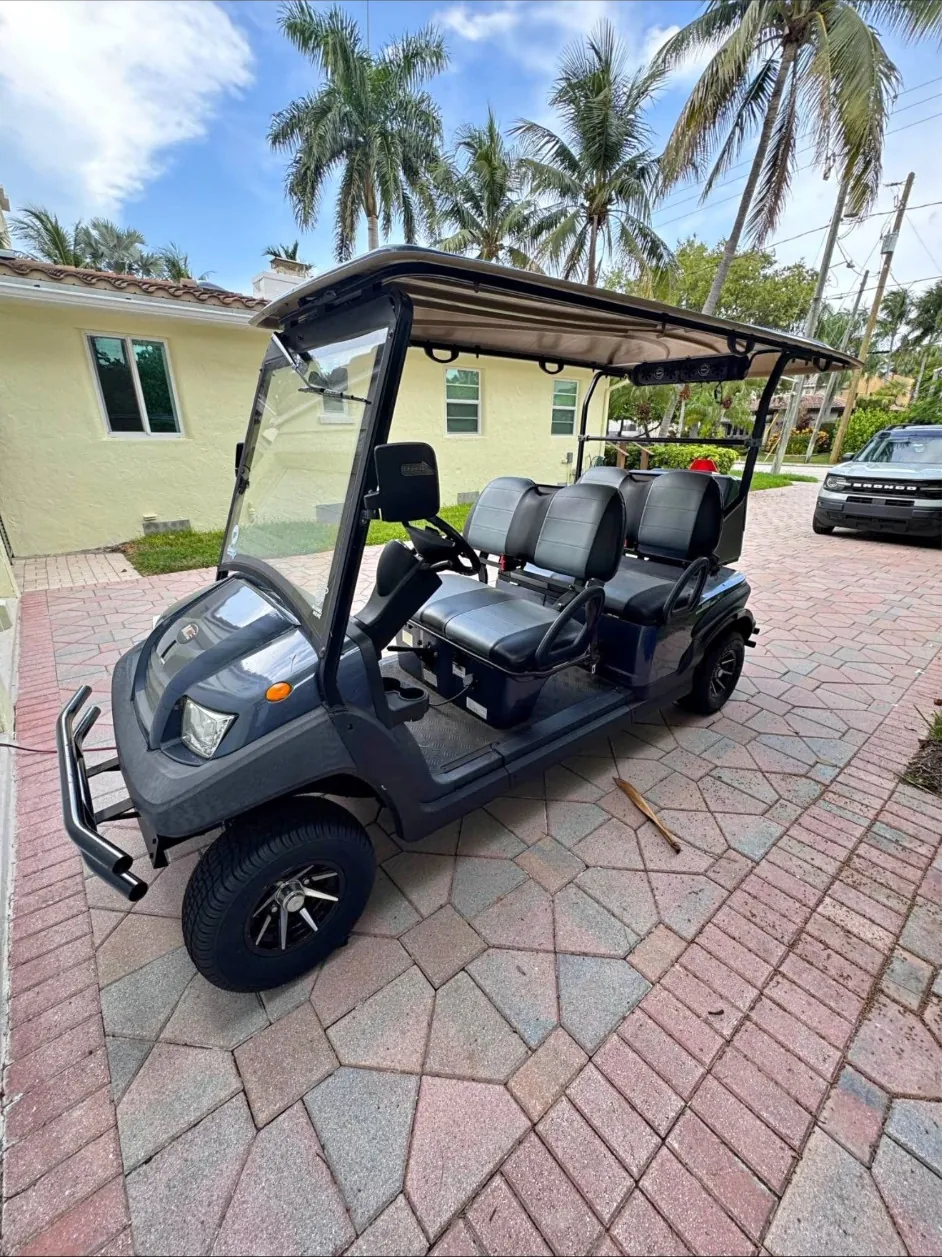 A six-seat SoFlo cart waiting on a paver driveway under palm trees.